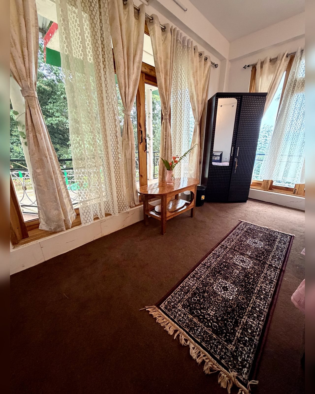 Bright room with sitting area, wardrobe and balcony windows at Kepchaki Stay, Lamahatta Darjeeling